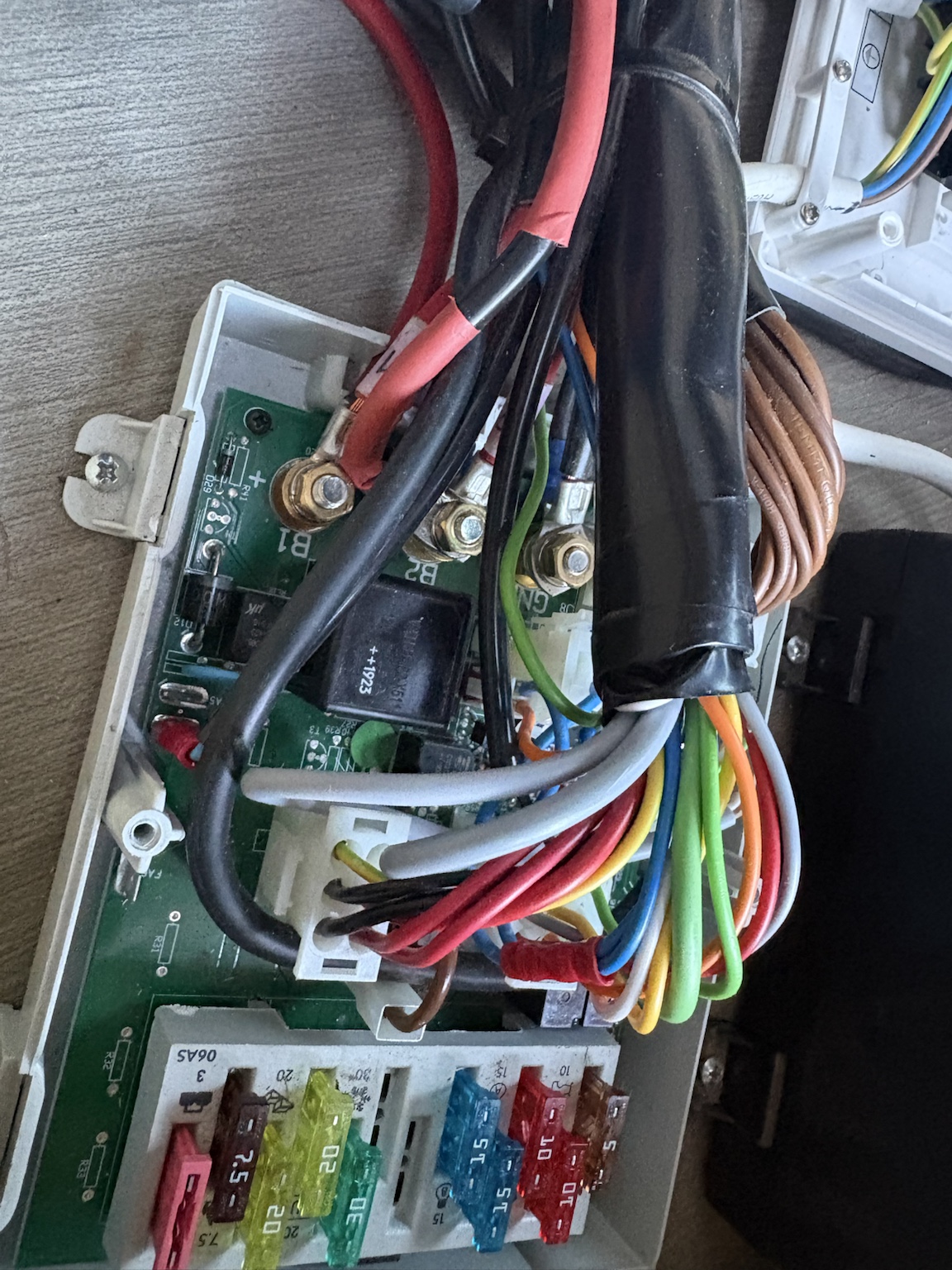 Nahaufnahme der geöffneten DS300. Die kräftigen Schraubanschlüsse B1, B2 und GND sind auf der Platine beschriftet. B1 und B2 liegen unmittelbar nebeneinander. Im Bereich der Batterieklemmen ist das zusätzlich verlegte Kabel mit rotem Schrumpfschlauch zu sehen, dessen beschädigte Isolation den unerwünschten Kontakt zwischen den beiden Batteriekreisen ermöglicht hatte.